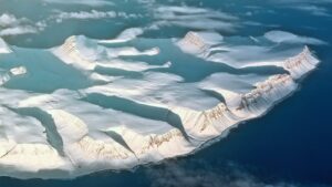Stunning bird's eye view of snow-capped mountains surrounded by icy ocean waters.